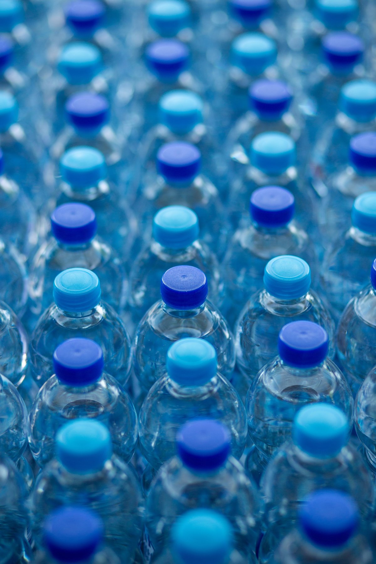 Botellas individuales de agua purificada de 500 ml con tapas azules, frías y con condensación.